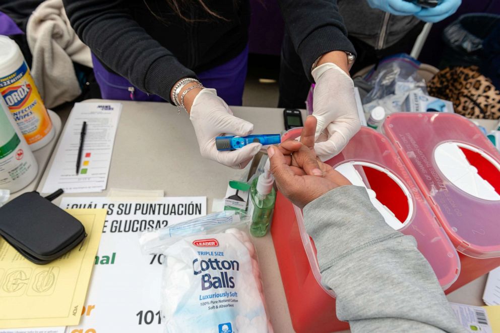 PHOTO: Volunteer nurses check patients' glucose levels and blood pressure.