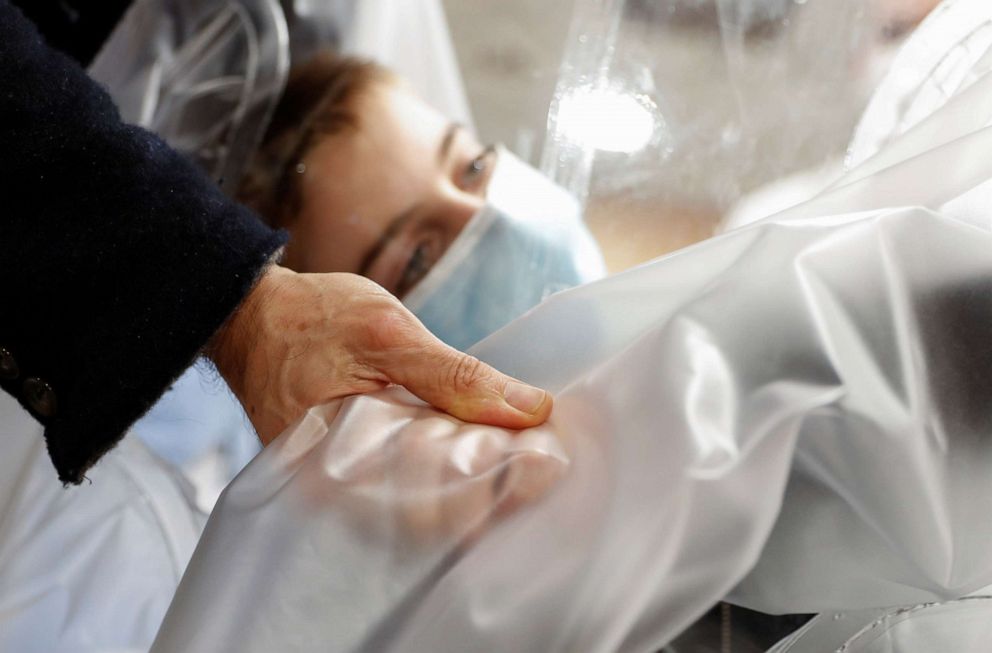 PHOTO: A hospitalized child holds his father's hand through plastic sheeting to avoid risk of contamination or transmission of the coronavirus disease at the San Raffaele hospital in Rome.