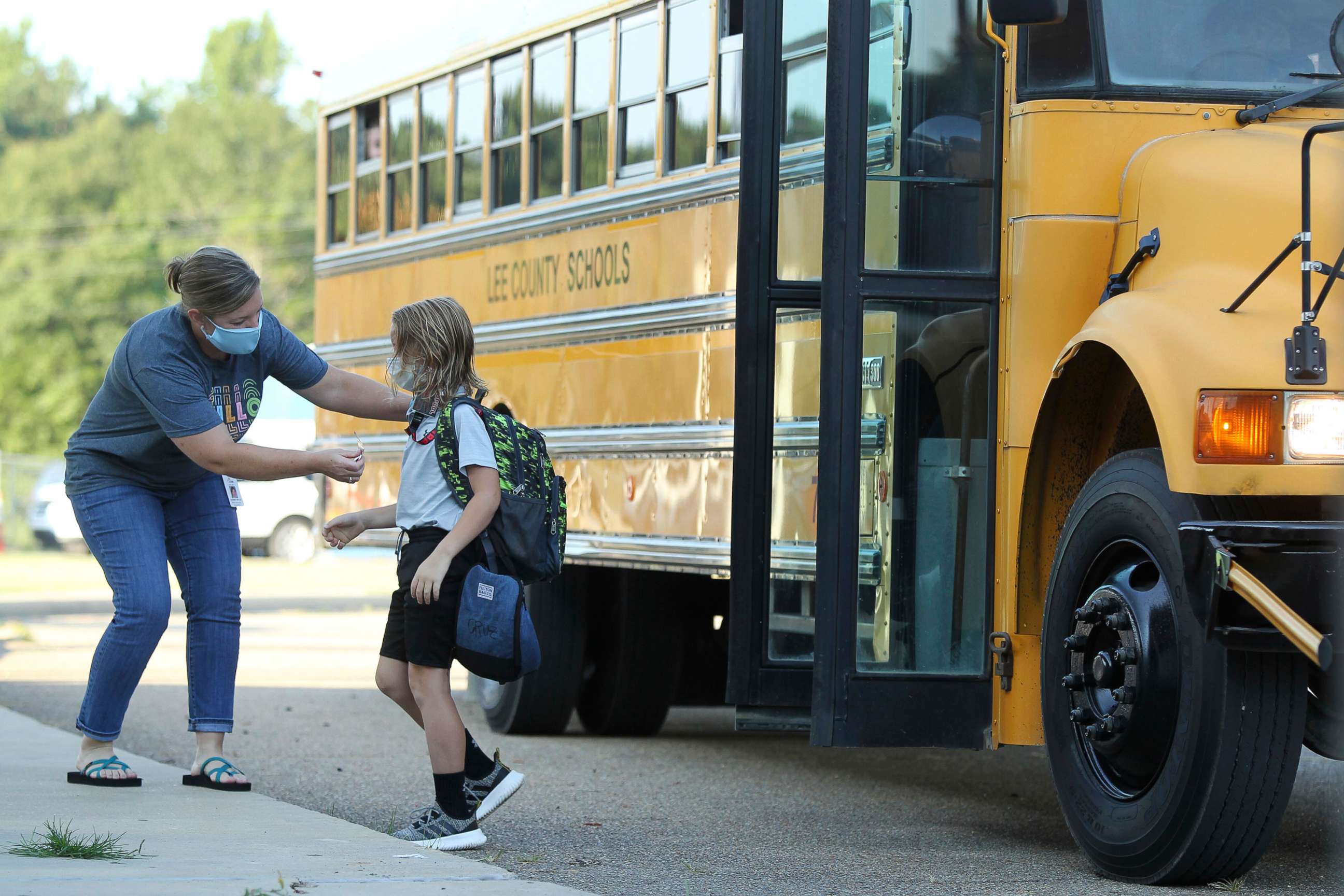 PHOTO: Audrey Wylie, a speech pathologist, at Saltillo Primary School, puts a bus number sticker on Cruz Antle, a first grader, as he gets off the bus for his first day back to school, Aug. 6, 2020, in Saltillo, Miss. 