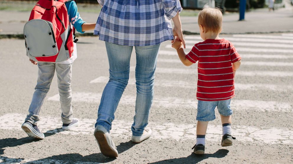 A mother walks with her two children on a crosswalk in this undated stock photo.