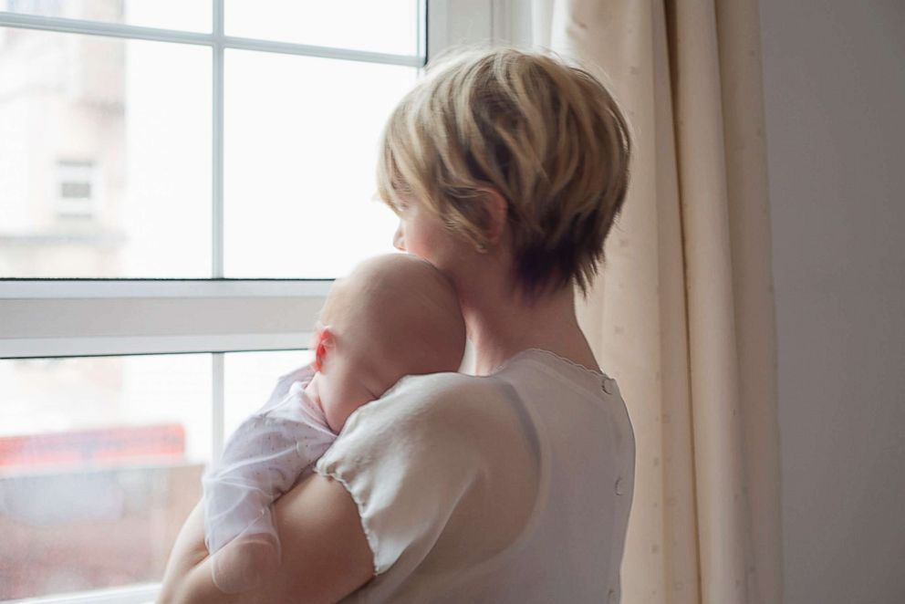 PHOTO: A mother holds her sleeping baby while looking out the window in this undated stock photo.