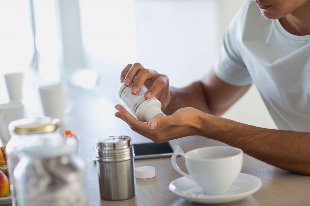 PHOTO: A young man taking nutritional supplement pills.