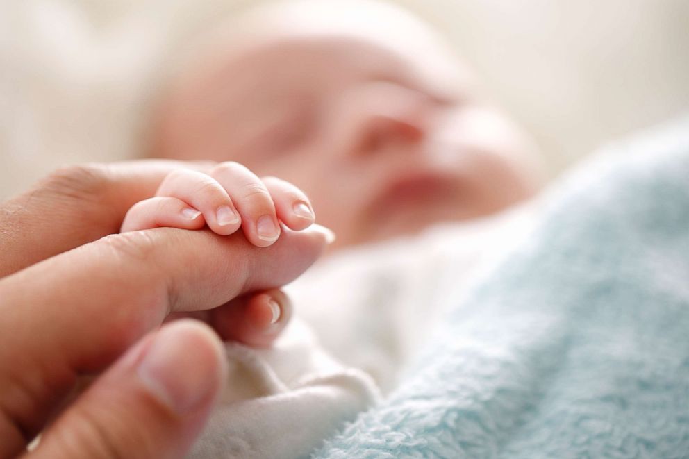 PHOTO: In this undated stock photo a sleeping baby clenches his parent's fingers.