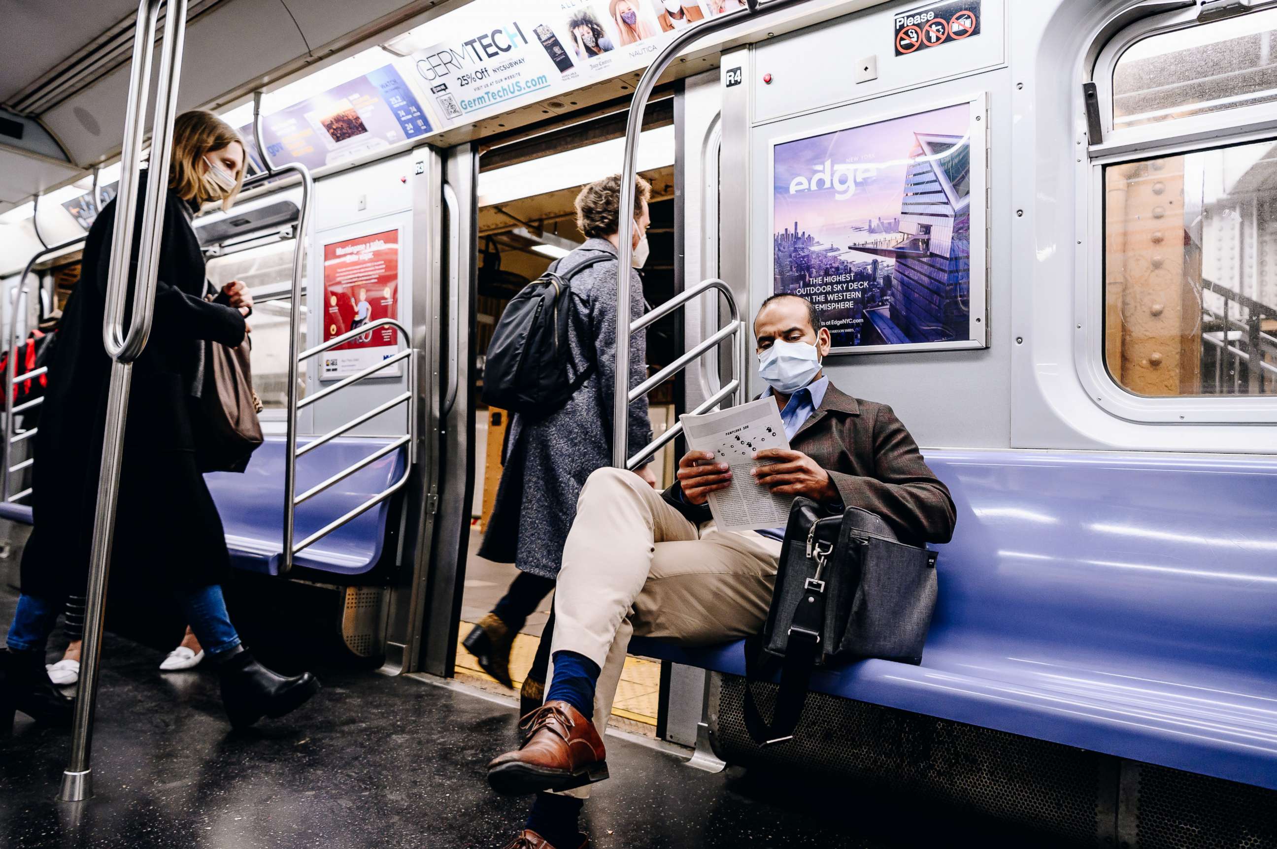 PHOTO: A passenger wearing a protective mask reads while riding on the L subway train in New York, April 13, 2021.