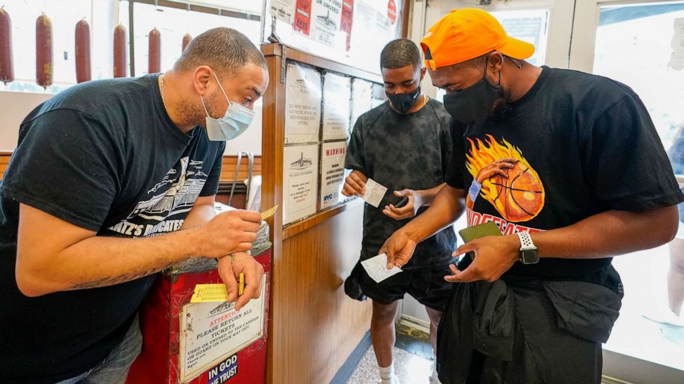 PHOTO: A Katz's Deli employee checks the proof of vaccination from customers who want to eat inside the restaurant, Aug. 17, 2021, in New York.