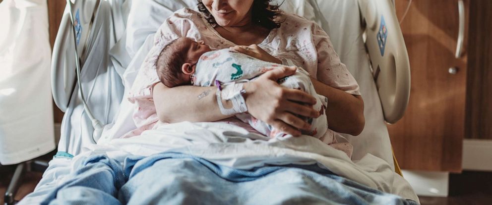 PHOTO: A woman holds a newborn baby in a hospital bed in an undated stock photo.