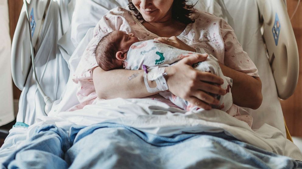 PHOTO: A woman holds a newborn baby in a hospital bed in an undated stock photo.