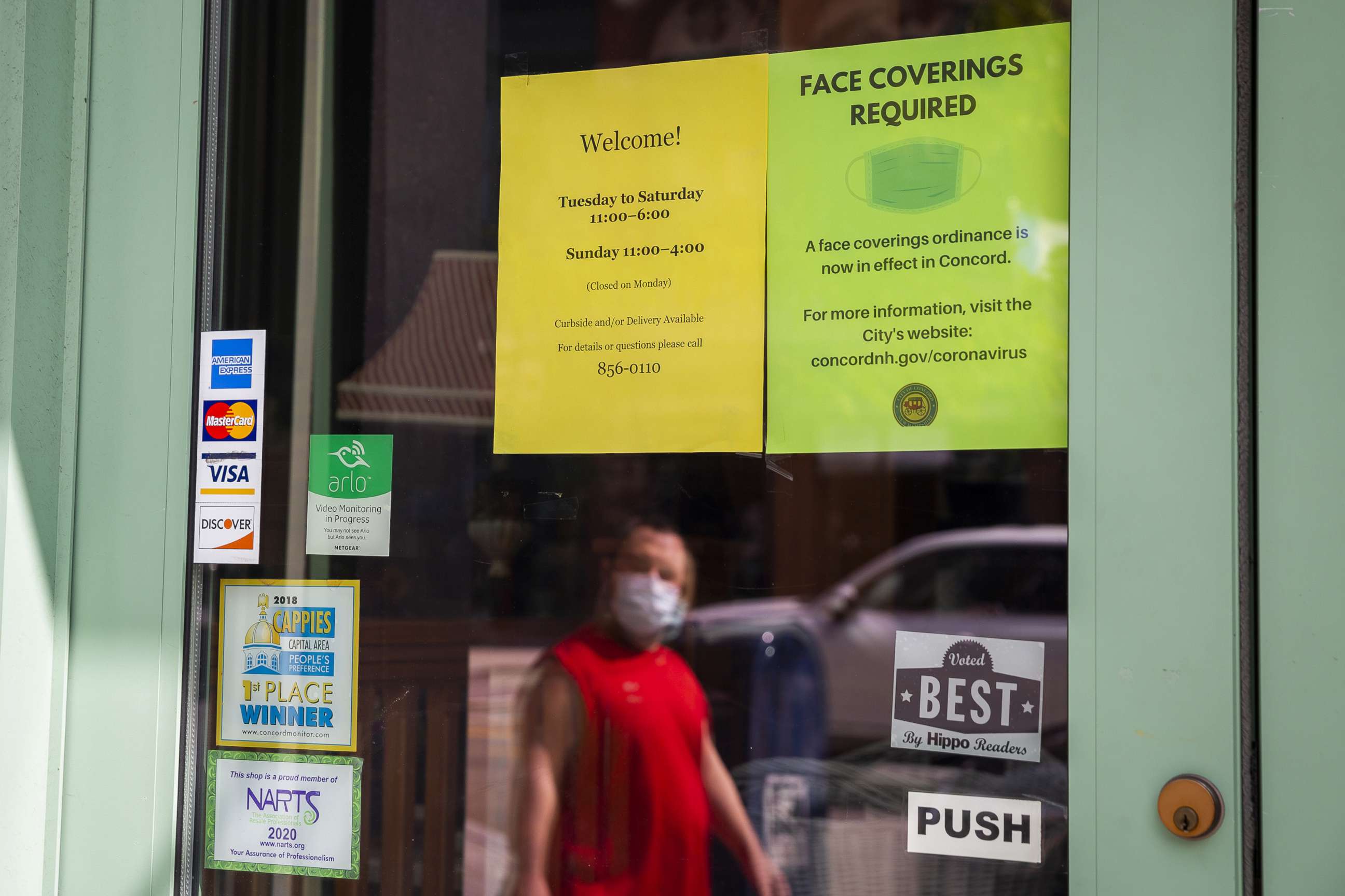 PHOTO: A pedestrian passes in front of a sign that reads "Face Coverings Required" outside a store in downtown Concord, N.H., Sept. 14, 2020.