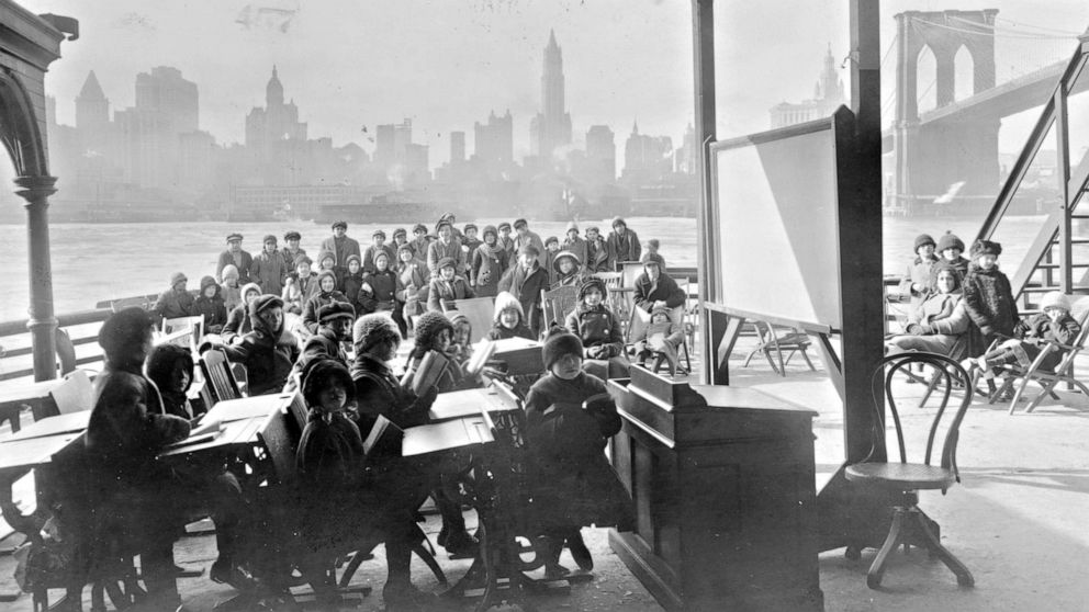PHOTO: An open air class on a ferryboat with Manhattan and the Brooklyn Bridge in the background, 1911.