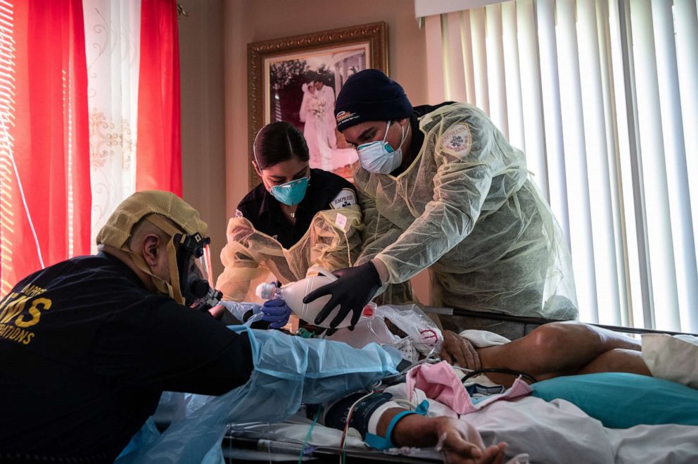 PHOTO: Medics wearing personal protective equipment (PPE), intubate a gravely ill patient with COVID-19 symptoms at his home on April 06, 2020 in Yonkers, New York. 