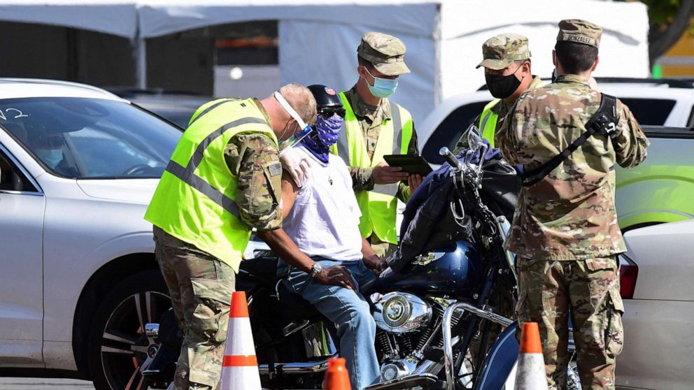 PHOTO: A motorcyclist receives his Covid-19 vaccine administered by members of the National Guard at a new mass Covid-19 vaccination site, on Feb. 16, 2021, at California State University of Los Angeles in Los Angeles.