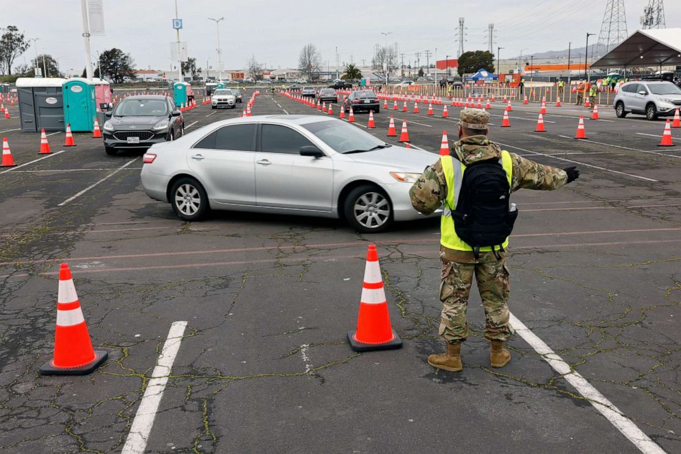 PHOTO: A National Guardsman directs traffic to the COVID-19 vaccination drive thru station during the opening of a large-scale COVID-19 community vaccination site at the Oakland Arena/RingCentral Coliseum in Oakland, Calif., Feb. 16, 2021.