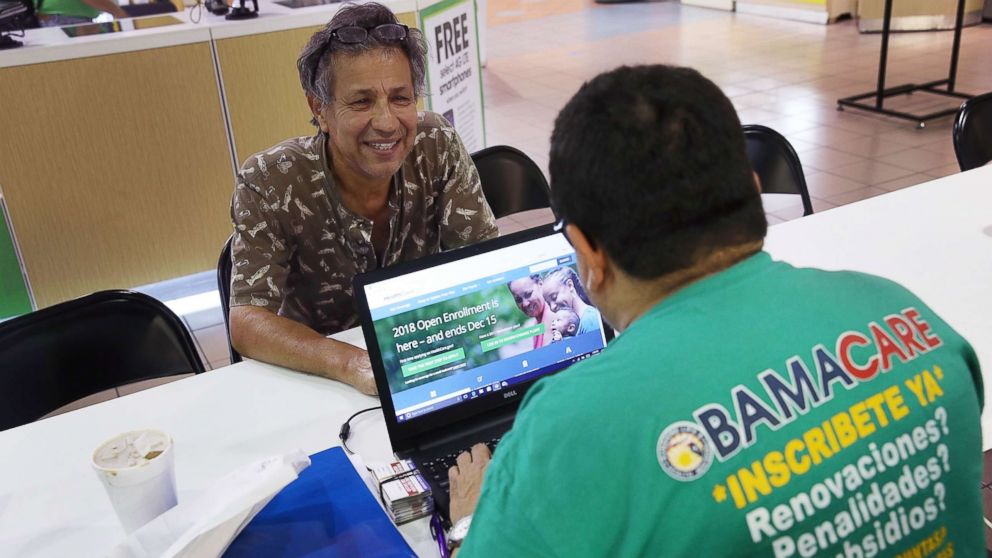 Rudy Figueroa, right, speaks with Marvin Mojica as he shops for insurance under the Affordable Care Act at a store setup in the Mall of America, Nov. 1, 2017 in Miami, Fla.
