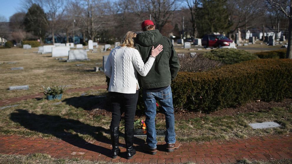 PHOTO: Family members embrace in a cemetery near the grave of a loved one who died of a heroin overdose.