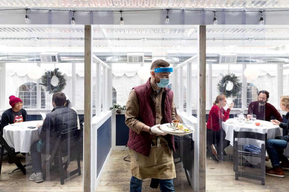 PHOTO: A waiter carries dishes from outdoor seating inside as indoor dining reopens in a limited capacity to reduce the spread of COVID-19 in Philadelphia, Jan. 16, 2021.