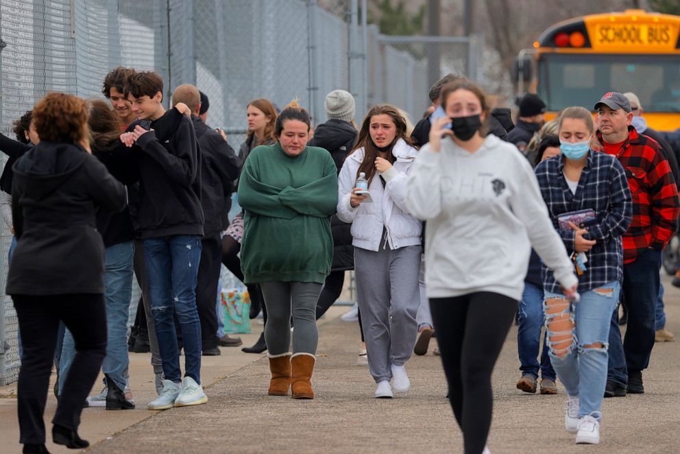 PHOTO: Parents walk away with their kids from the Meijer's parking lot in Oxford where many students gathered following an active shooter situation at Oxford High School in Oxford, Mich., Nov. 30, 2021.