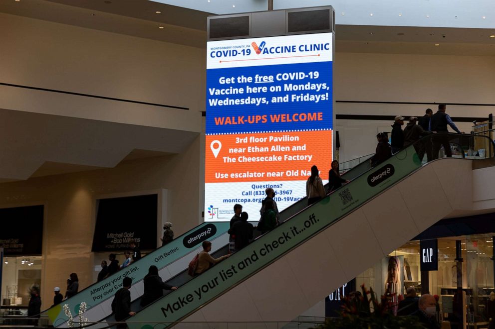 PHOTO: People ride an escalator past a sign for a COVID-19 vaccine clinic at the King of Prussia mall in King of Prussia, Pa., Dec. 4, 2021.