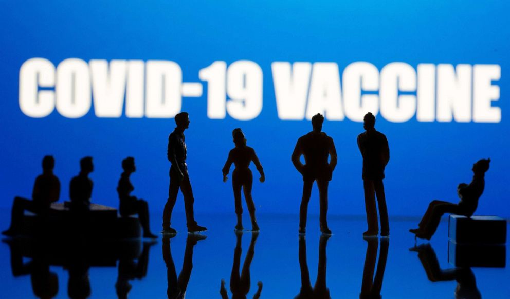 PHOTO: Small toy figures are seen in front of a COVID-19 vaccine logo in this photo illustration from Sept. 9, 2020.