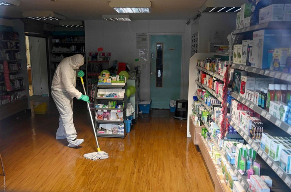 PHOTO: A worker in protective clothing, including face mask and gloves, cleans the floor of the pharmacy attached to the  County Oak Medical Centre in Brighton, England, Feb. 10, 2020.