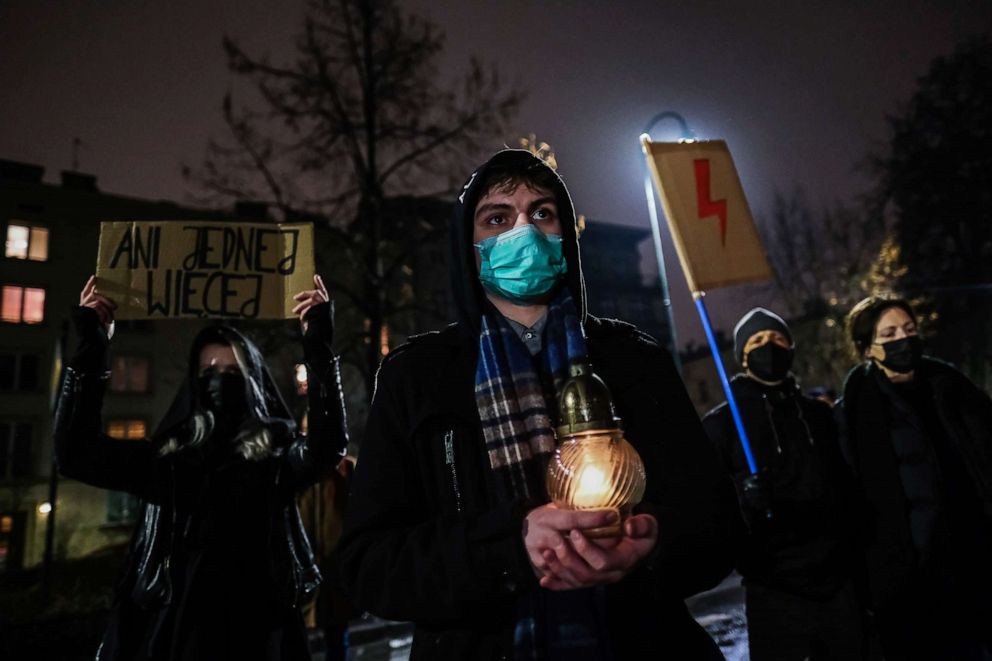 PHOTO: People wear a protective face masks and hold banners and candles during a protest in front of the Law and Justice party office on Jan. 26, 2022 in Krakow, Poland.