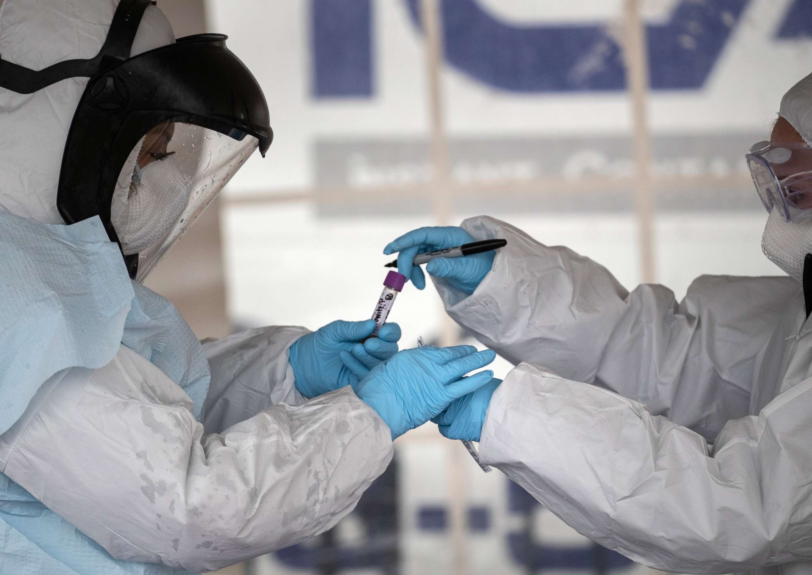 PHOTO: Health workers dressed in personal protective equipment (PPE) handle a coronavirus test at a drive-thru testing station at Cummings Park on March 23, 2020 in Stamford, Connecticut.