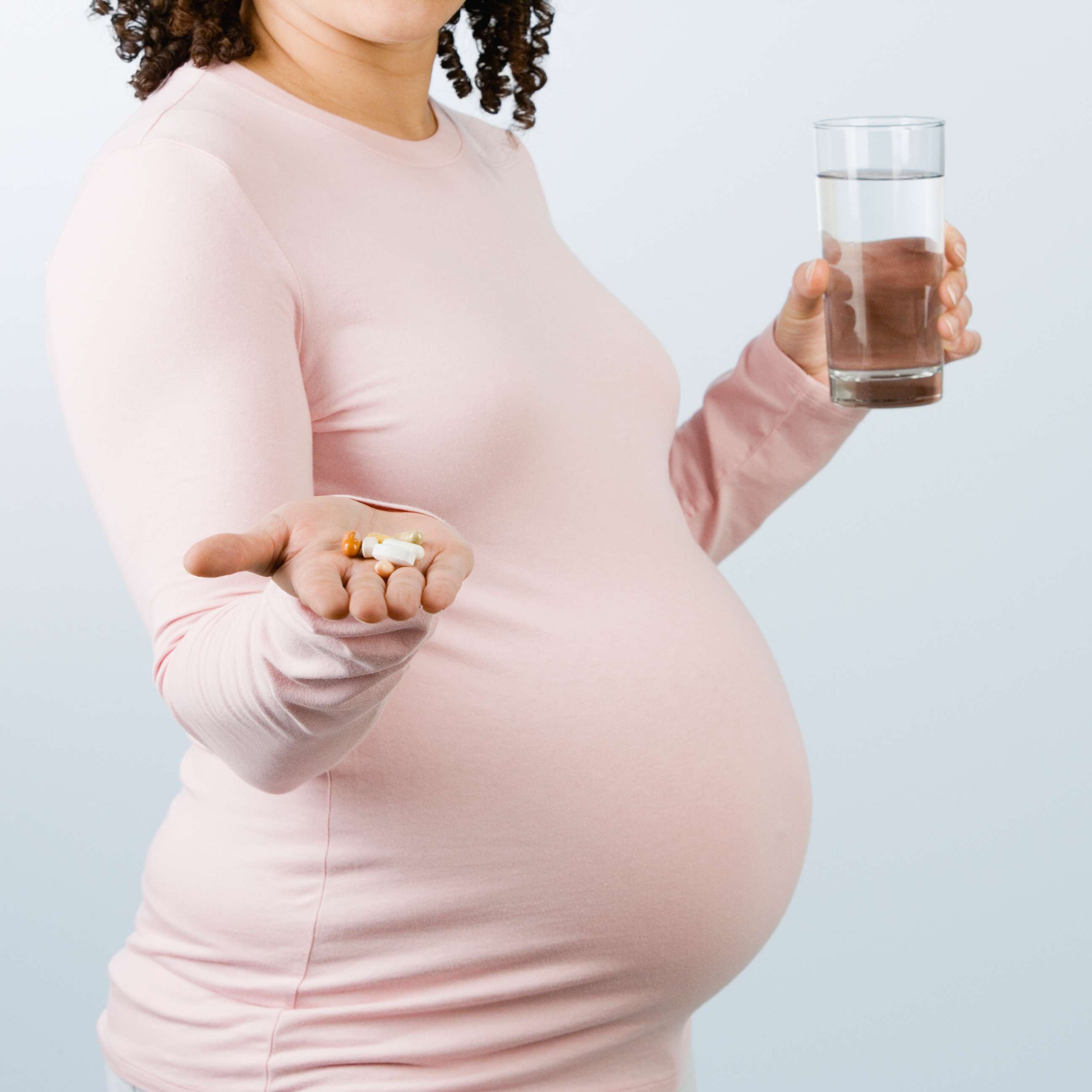 PHOTO: A stock photo of a pregnant woman holding pills and a glass of water. 