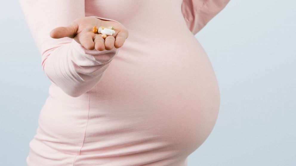 PHOTO: A stock photo of a pregnant woman holding pills and a glass of water. 