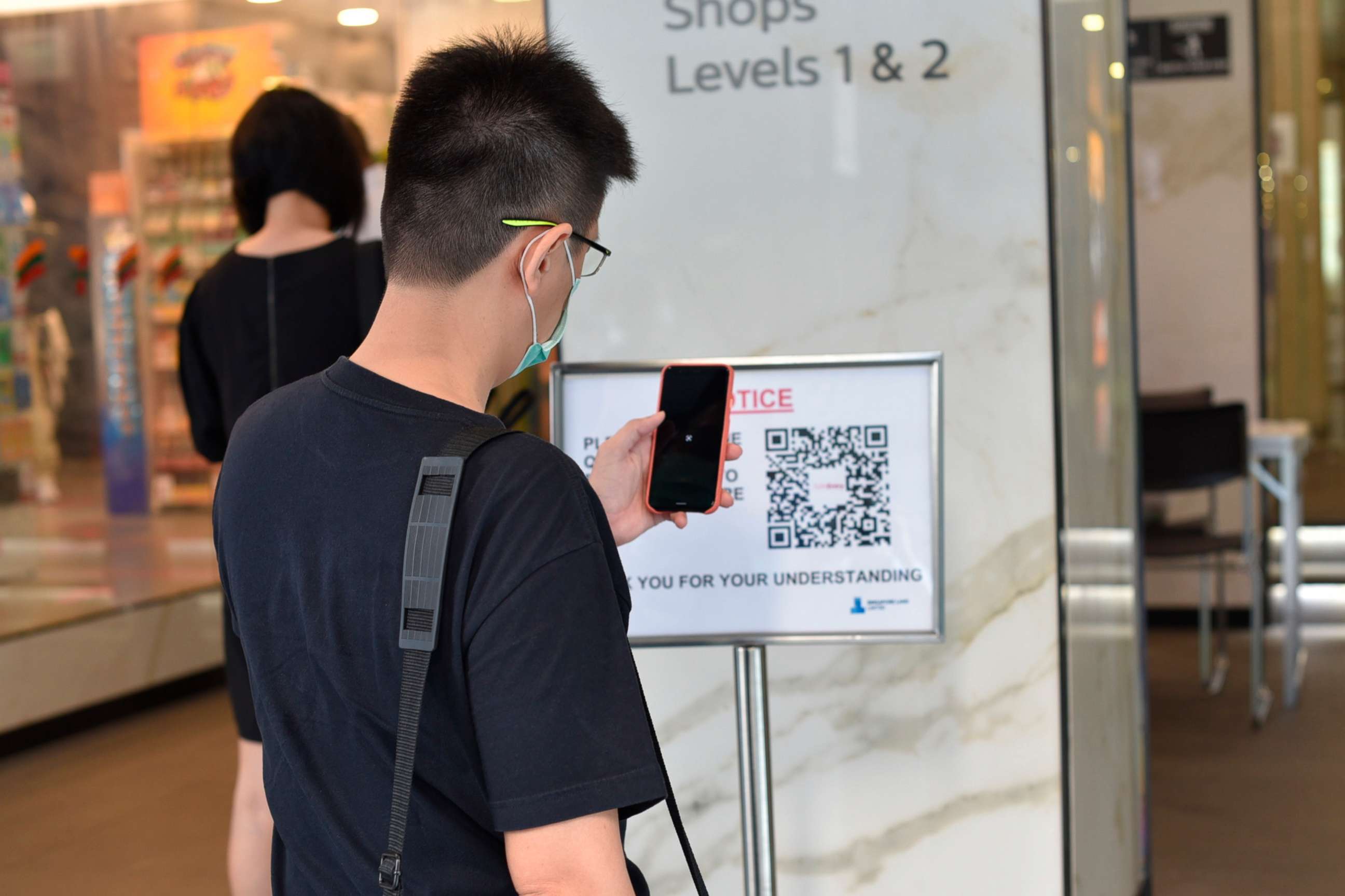 PHOTO: A man scans a QR code before entering a building in Singapore Tuesday, June 2, 2020. Singapore reopened 75% of its economy Tuesday, as part of a three-phase controlled approach to end a virus lockdown since early April.