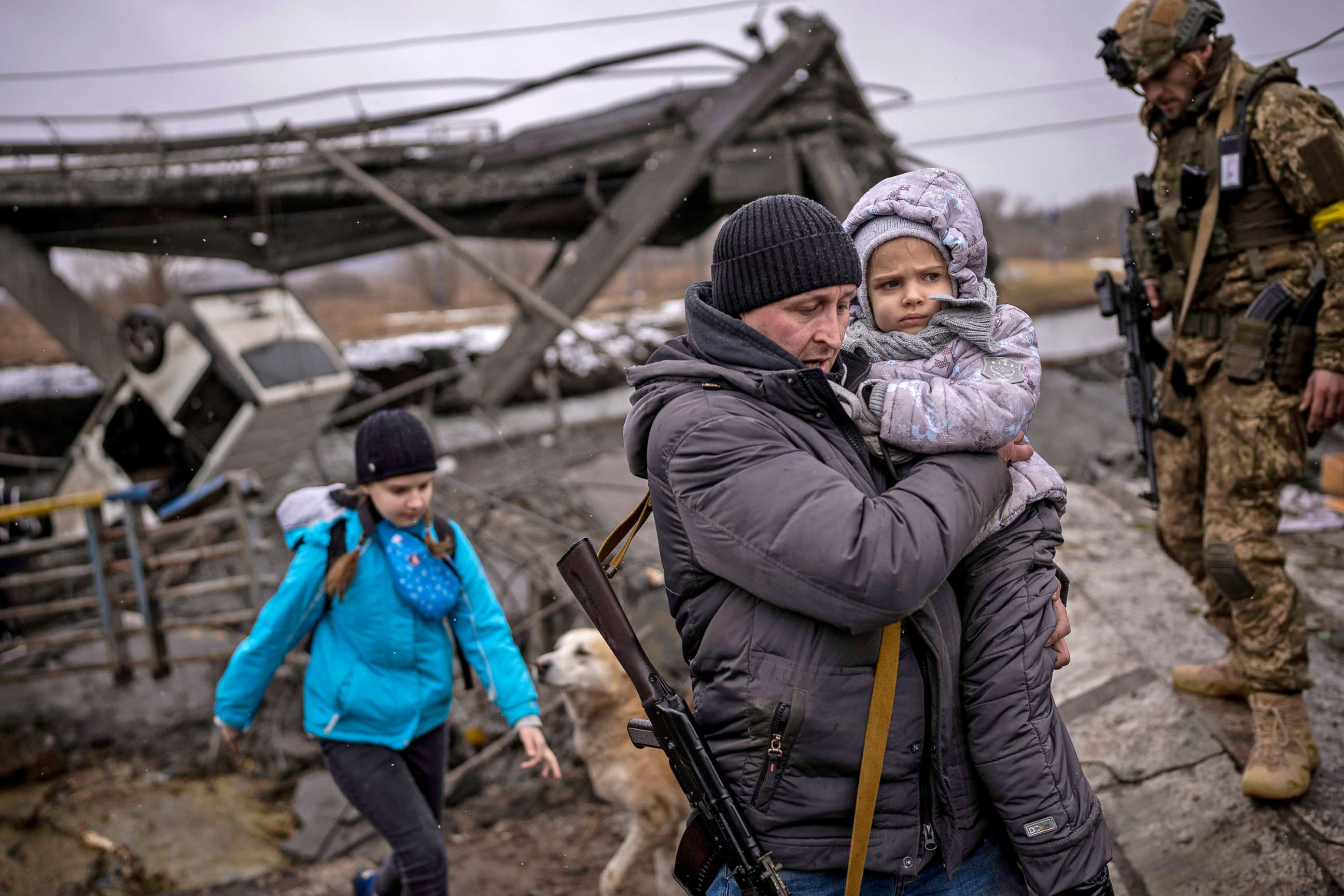 PHOTO: Local militiaman Valery, 37, carries a child as he helps a fleeing family across a bridge destroyed by artillery, on the outskirts of Kyiv, Ukraine, March 2.