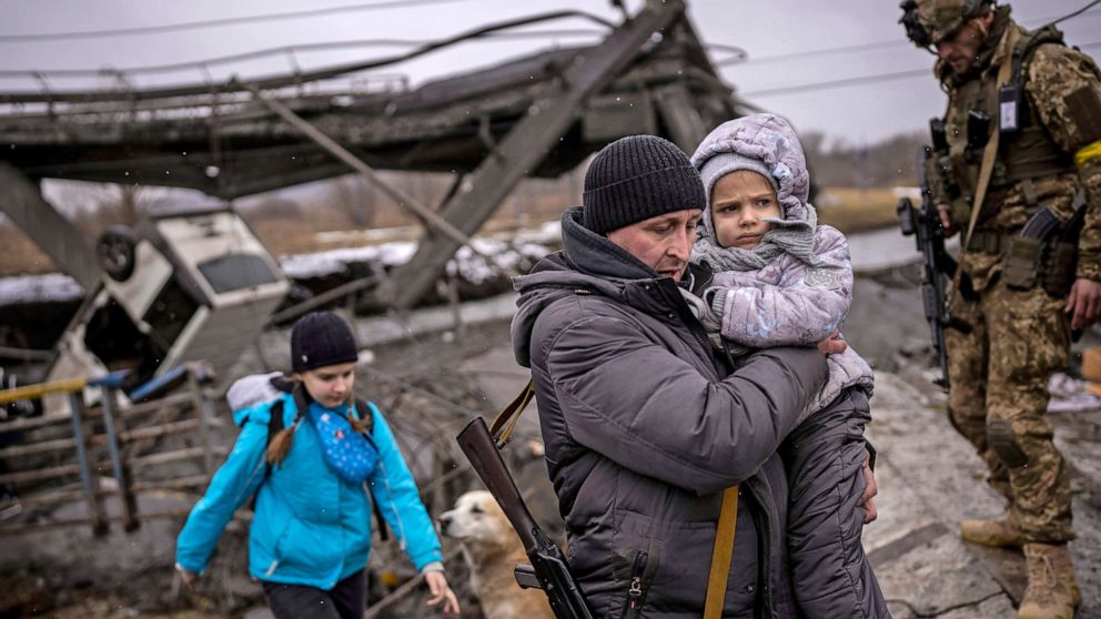 PHOTO: Local militiaman Valery, 37, carries a child as he helps a fleeing family across a bridge destroyed by artillery, on the outskirts of Kyiv, Ukraine, March 2.