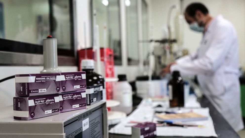 PHOTO: In this June 29, 2020, file photo, packs containing vials of Remdesivir, a broad-spectrum antiviral medication approved as a specific treatment for COVID-19, lie next to an employee of Eva Pharma at the company's factory in Giza, Egypt.