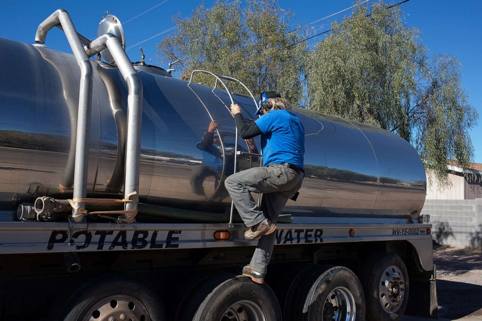 PHOTO: John Hornewer climbs down the ladder of his tanker as he fills it up to haul water to Rio Verde Foothills, Jan. 7, 2023, in Apache Junction, Ariz.