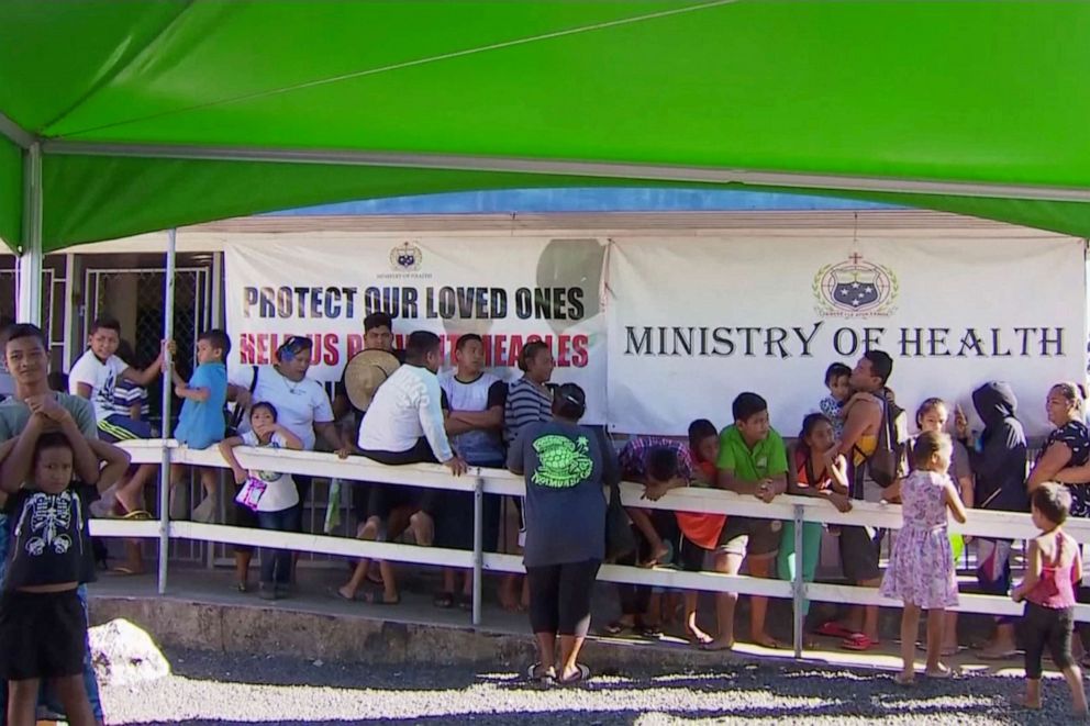 PHOTO: In this November 2019, image from video, children with parents wait in line to get vaccinated outside a health clinic in Apia, Samoa. 