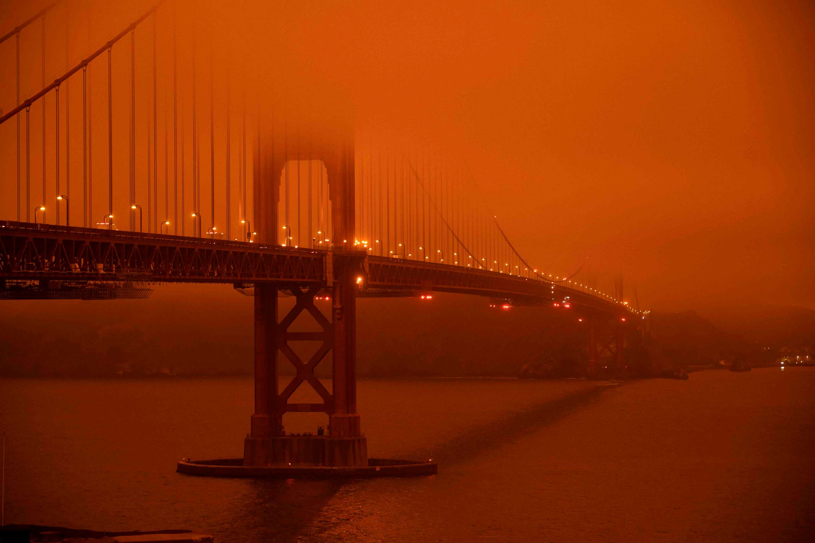 PHOTO: Cars drive along the Golden Gate Bridge under an orange smoke filled sky at midday in San Francisco, Sept. 9, 2020.