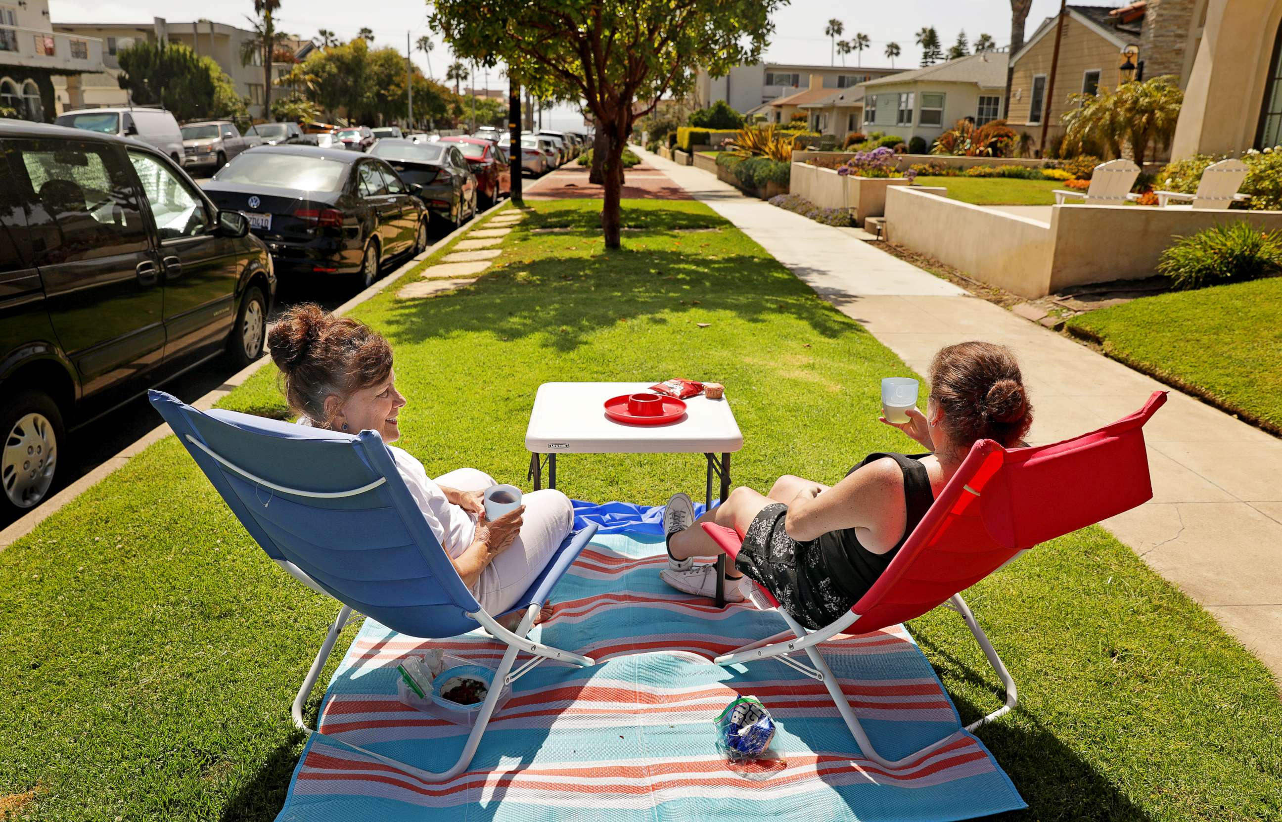 PHOTO: Neighbors Leah Mitchell, left, and Ellen Dougherty enjoy the sun from the parkway in front of their homes in Redondo Beach on Sunday, May 24, 2020.