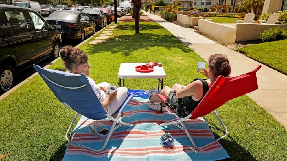 PHOTO: Neighbors Leah Mitchell, left, and Ellen Dougherty enjoy the sun from the parkway in front of their homes in Redondo Beach on Sunday, May 24, 2020.