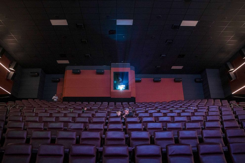 PHOTO: Daniel Curtis and his son Aidan are two of only eight patrons in the audience for a 1p.m. showing in the Playa Vista neighborhood of Los Angeles, as the theater reopens with covid-19 restrictions loosened, March 15, 2021.