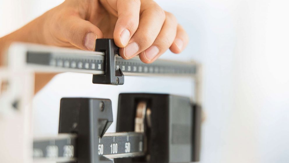 PHOTO: Stock photo of a person using a scale to weigh themselves. 