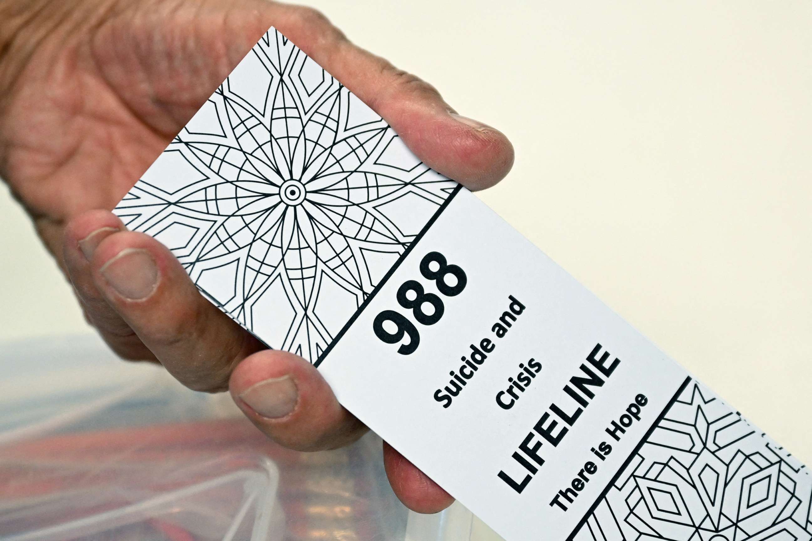 PHOTO: A bookmark for children with the 988 suicide and crisis lifeline emergency telephone number is displayed by Lance Neiberger while they speak about mental health and suicide awareness in Casper, Wy., Aug. 14, 2022.