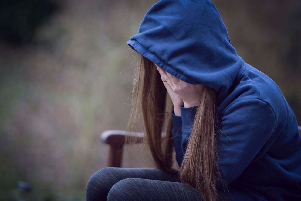 PHOTO: This undated stock photo shows a young woman sitting alone and covering her face with her hands.