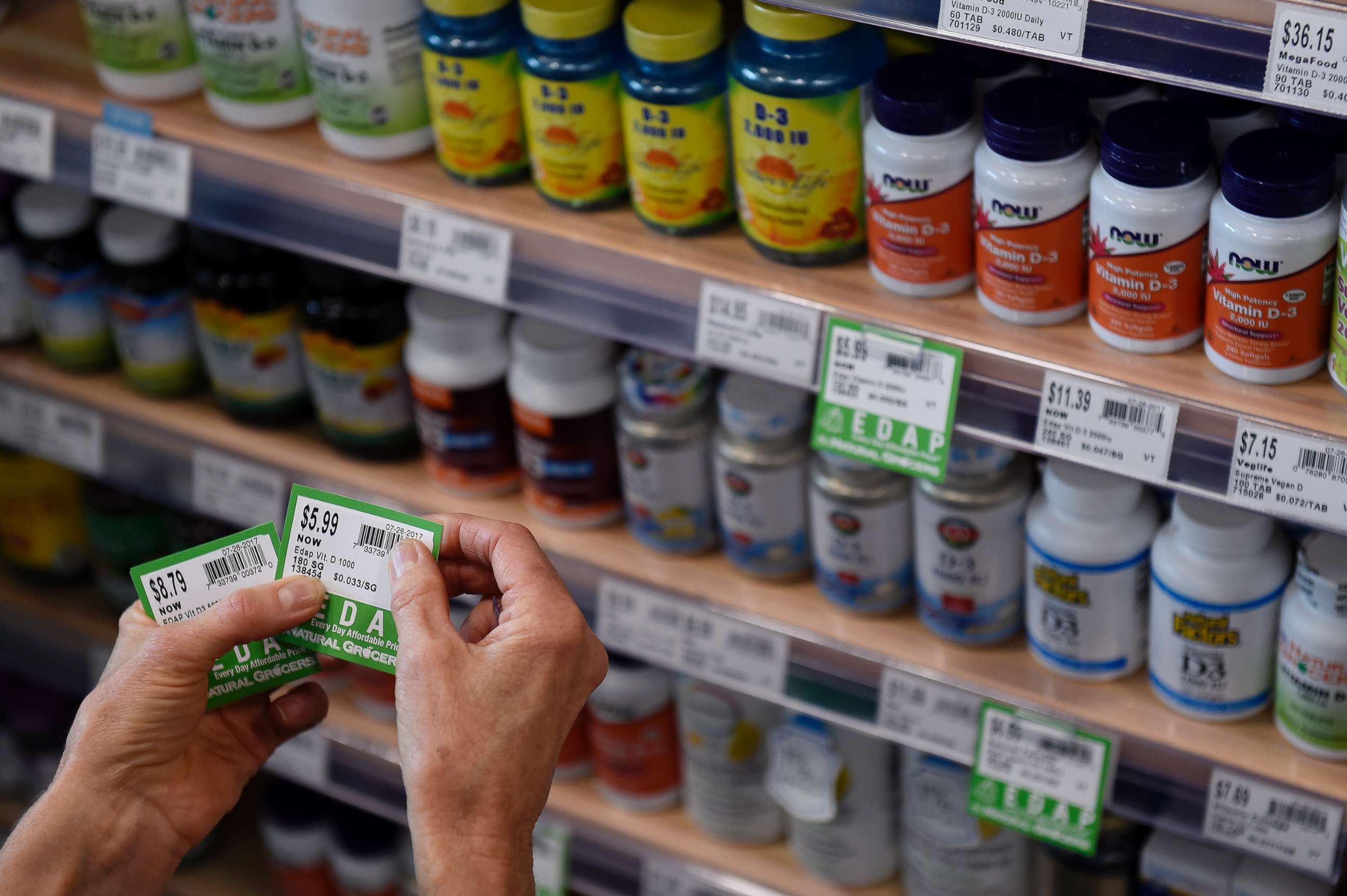 PHOTO: A store worker affixes price tags to vitamins at a grocery storey on July 26, 2017, in Denver.