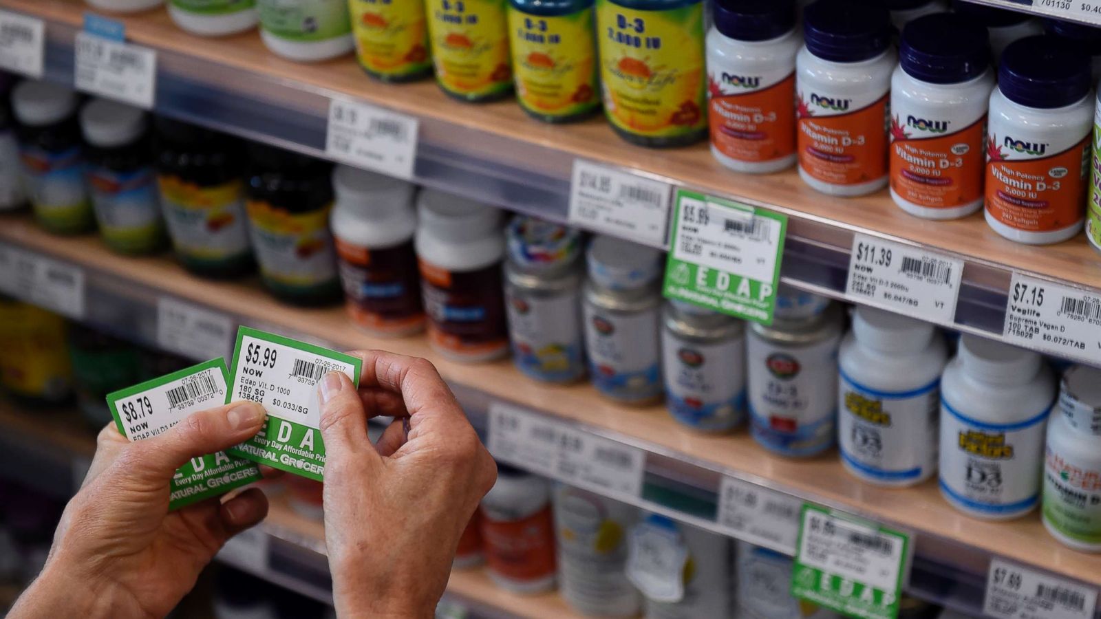 PHOTO: A store worker affixes price tags to vitamins at a grocery storey on July 26, 2017, in Denver.