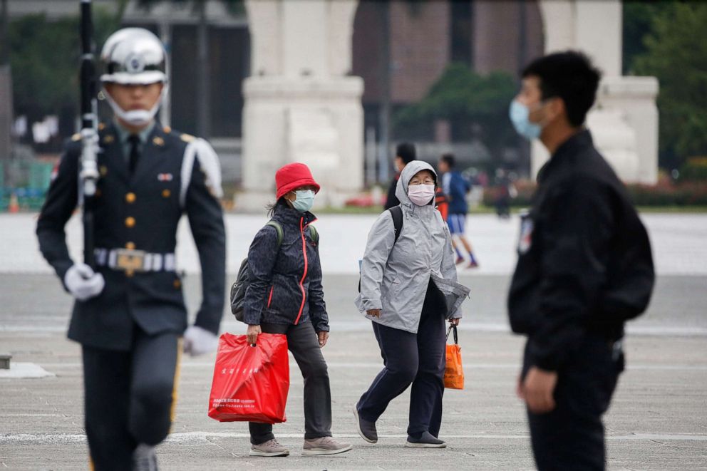 PHOTO: Tourists wear protective face masks to protect themselves from the coronavirus while passing by a flag rising ceremony at Chiang Kai Shek Memorial Hall in Taipei, Taiwan, March 11, 2020. 
