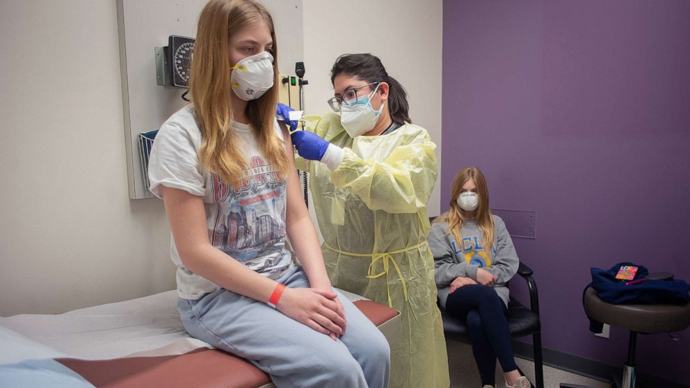 PHOTO: Isabelle King, 14, gets her second dose of the Moderna vaccine from Jallesse Flores, as her twin sister watches, Feb. 5, 2021, in Houston.