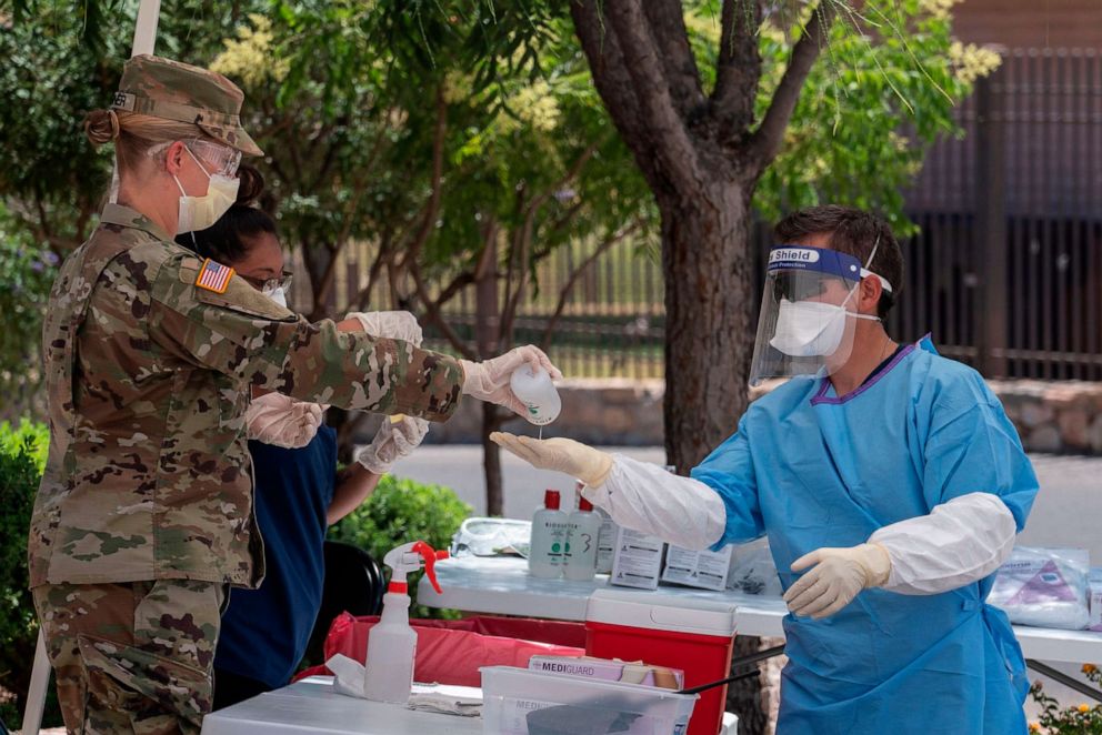 PHOTO: Private First Class Armon Ramirez from the Texas National Guard is given hand sanitizer after testing people for COVID-19 in the parking lot of Memorial Swimming Pool on May 18, 2020 in El Paso, Texas.