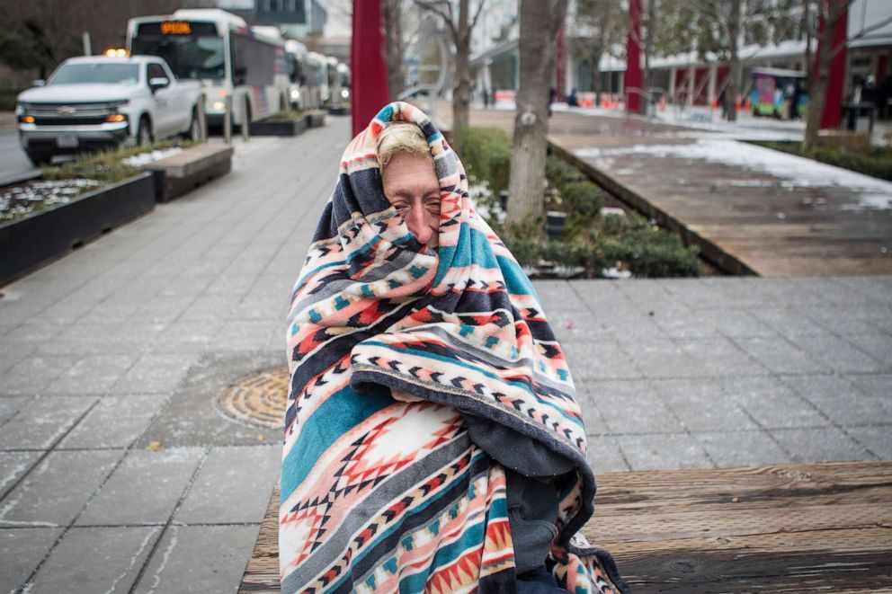 PHOTO: Michelle DeFord bundles up in a blanket to stay warm outside the warming shelter at the George R. Brown Convention Center, where she is staying during the frigid cold weather, Feb. 16, 2021, in Houston.