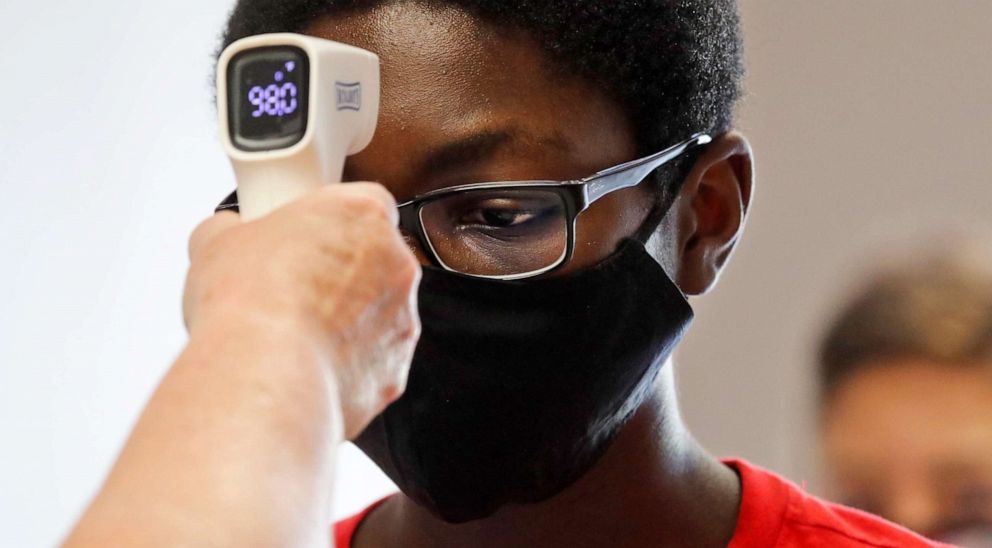 PHOTO: A young student has his temperature checked by a teacher before entering a summer STEM camp at Wylie High School Tuesday, July 14, 2020, in Wylie, Texas.