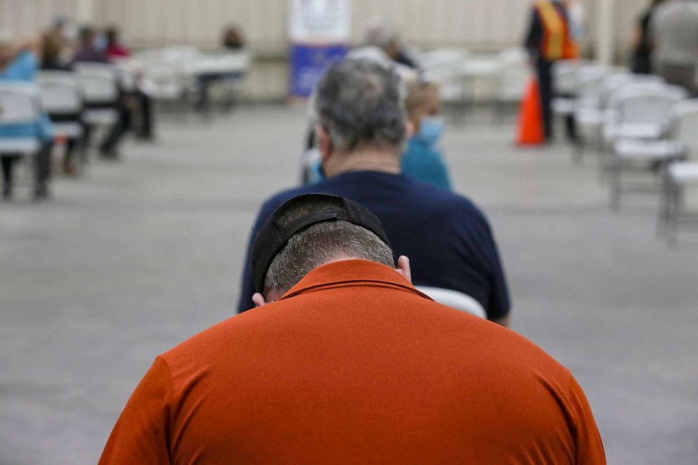 PHOTO: A man lowers his head as he waits in the registration area, Jan. 5, 2021, at the COVID-19 vaccination clinic on the Rio Grande Valley Livestock Show grounds in Mercedes, Texas.