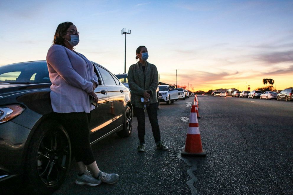 PHOTO: Cindy Rubiano and Trolena Loya stand outside their car as they wait in line overnight on behalf of their aged parents and in-laws, Jan. 7, 2021, before the COVID-19 vaccine clinic at Casa Del Sol opened on Friday morning in Harlingen, Texas.
