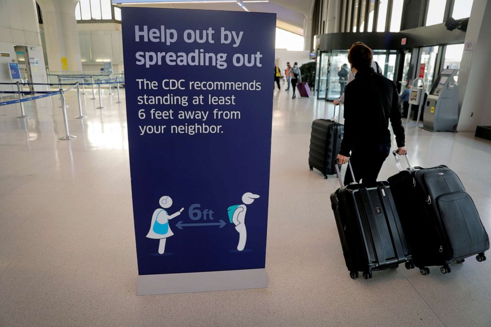 PHOTO: Travelers pass a social-distancing sign as they arrive to check in for flights ahead of the Thanksgiving holiday at Newark International Airport in Newark, N.J., Nov. 25, 2020.